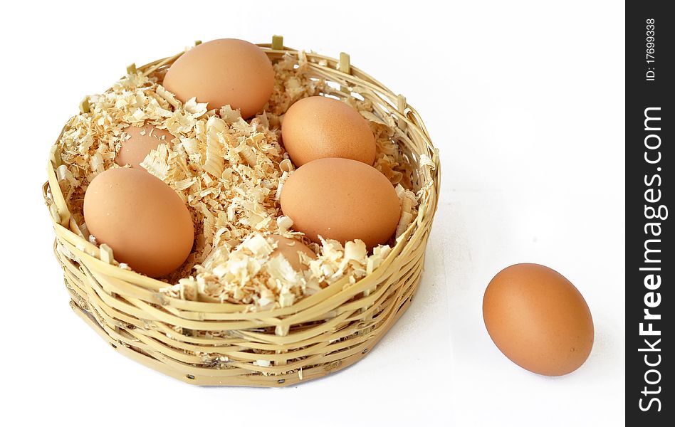 Chicken eggs in a straw basket with wood shreds to remove humidity. Chicken eggs in a straw basket with wood shreds to remove humidity.