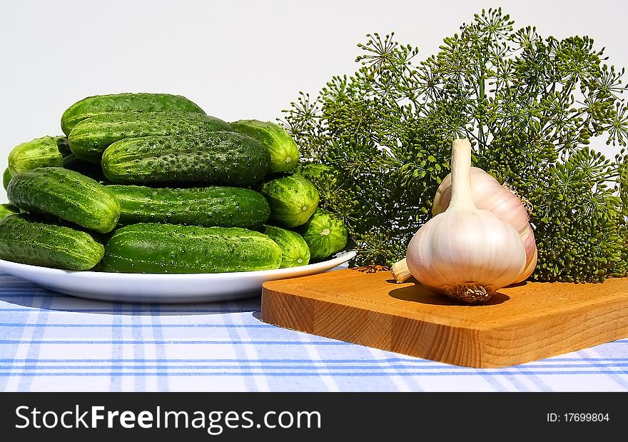 Fresh cucumbers, garlic and dill on a table.