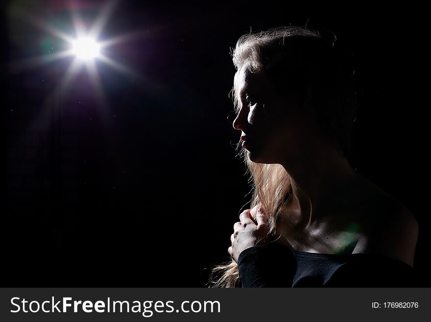 Portrait Of A Girl Illuminated By The Contour Light Of A Flash On A Black Background