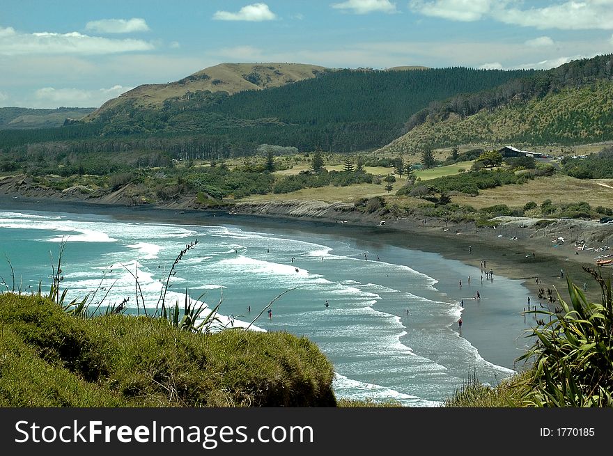 Wave breaking into remote balck sand coast line with swimmers. Wave breaking into remote balck sand coast line with swimmers