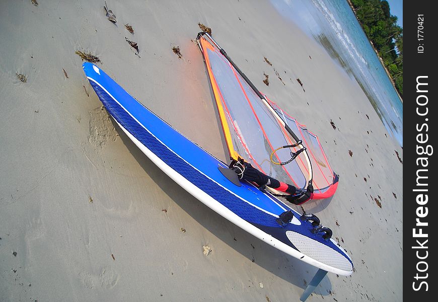 Single blue windsurf board lying on the beach at Bintan, Indonesia
