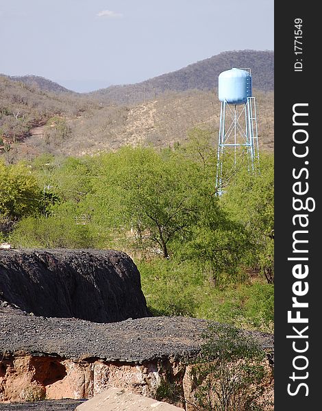 Abandoned road and water tank in the back in front of the foothill of the Sierra Madre in the town of Alamos, in the northern state of Sonora, Mexico, Latin America