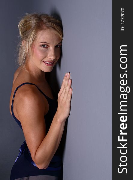 Beautiful blond girl leaning against a grey wall looking at the camera. Beautiful blond girl leaning against a grey wall looking at the camera