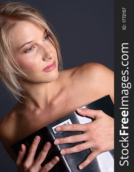 Beautiful naked blond girl covering body with black magazine (looking down). Beautiful naked blond girl covering body with black magazine (looking down)