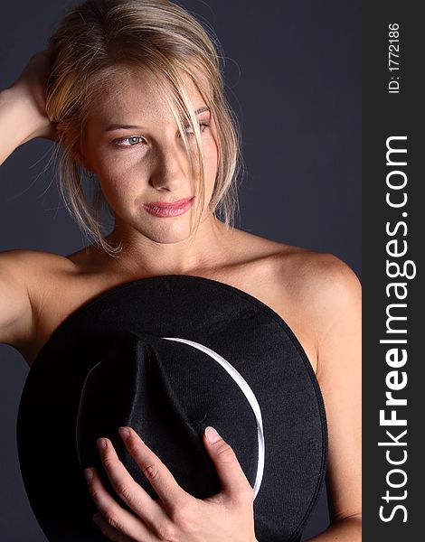 Beautiful naked blond girl covering body with black hat (with arm). Beautiful naked blond girl covering body with black hat (with arm)
