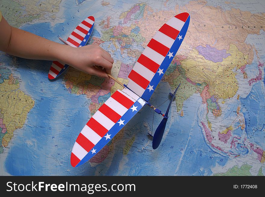 The airplane in the girl's hand at the map. The airplane in the girl's hand at the map