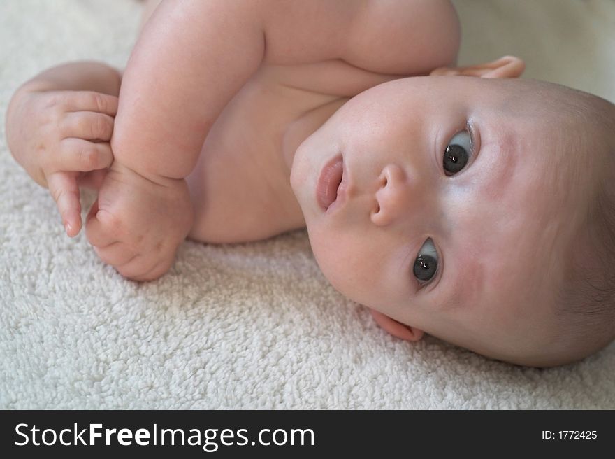 Image of baby boy lying down on a blanket, looking at the camera. Image of baby boy lying down on a blanket, looking at the camera