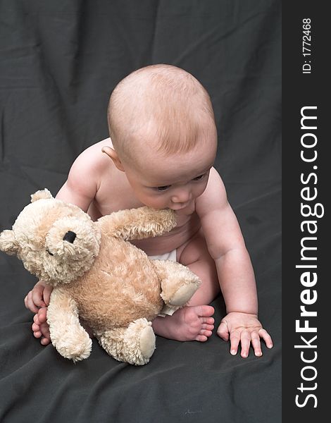Image of baby boy sitting up holding a teddy bear. Image of baby boy sitting up holding a teddy bear