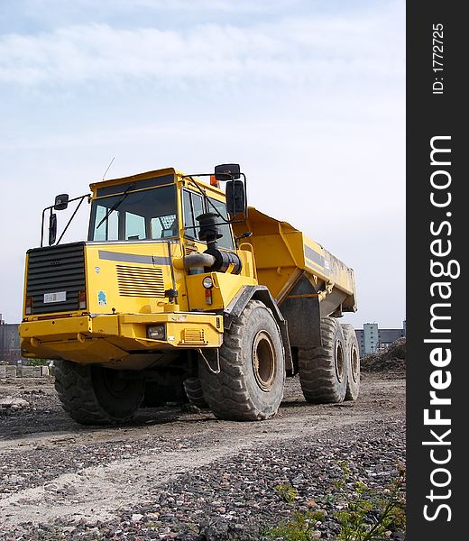 Portrait of dump truck on path with sky background