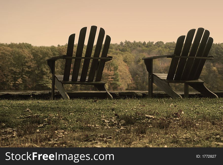 Taken at a state park in Massachusetts, USA. Made to look aged and old with a sepia filter over color, not black and white. Two adirondack chairs in a grassy scene. Taken at a state park in Massachusetts, USA. Made to look aged and old with a sepia filter over color, not black and white. Two adirondack chairs in a grassy scene.