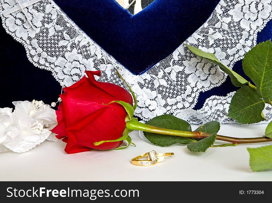 Beautiful engagement and wedding rings and a perfect red rose sit in front of a lacy, blue wedding photo album. Valentines Special!. Beautiful engagement and wedding rings and a perfect red rose sit in front of a lacy, blue wedding photo album. Valentines Special!