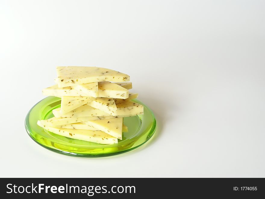 Sliced cheese on the green plate close-up