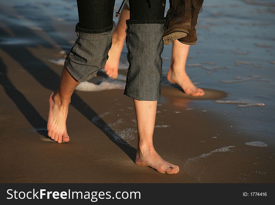 Two pairs female legs on wet sand. Two pairs female legs on wet sand