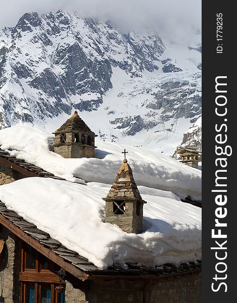 Snow roofs and chimneys on a background of mountains