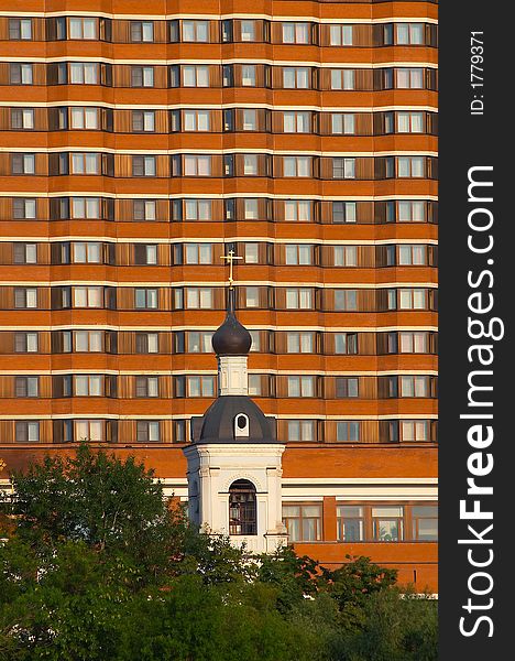 Small church on a background of huge hotel