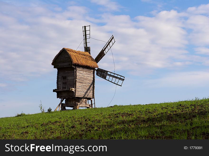 Windmill with a straw roof on a green meadow