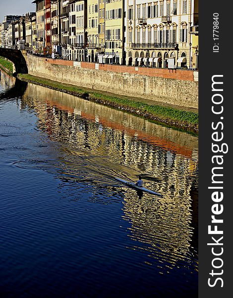 A rower practicing in the Arno river, Florence, Italy. View gives a peacful feeling. A rower practicing in the Arno river, Florence, Italy. View gives a peacful feeling.