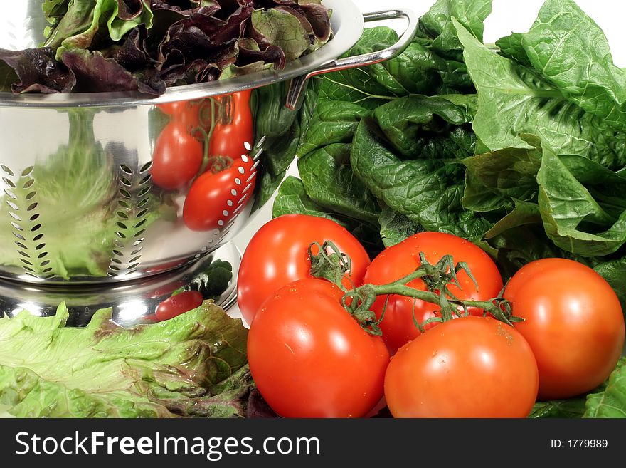 This is an image of vine ripened tomatoes, lettuce, and a colander. This is an image of vine ripened tomatoes, lettuce, and a colander.