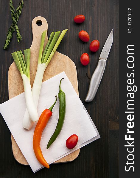 Fresh peppers and leeks on wooden background