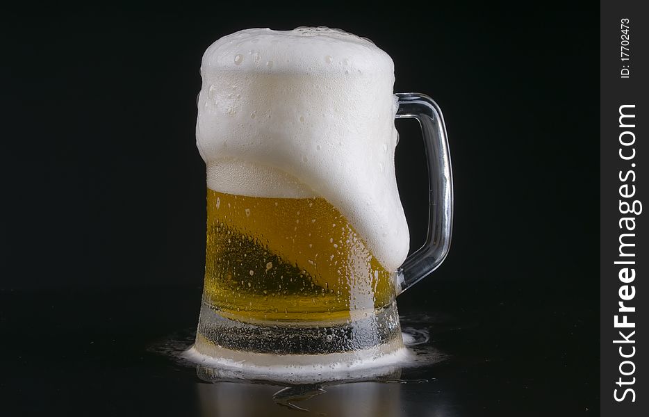 A light beer foaming over the rim of a frosty mug. A light beer foaming over the rim of a frosty mug.