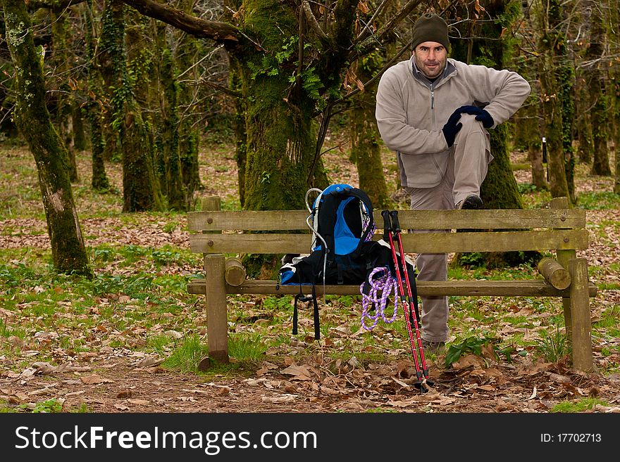 Hiker stretching with gear over a wood bench