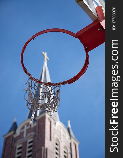 A look upwards at a tattered basketball hoop with a church steeple showing through. A look upwards at a tattered basketball hoop with a church steeple showing through.