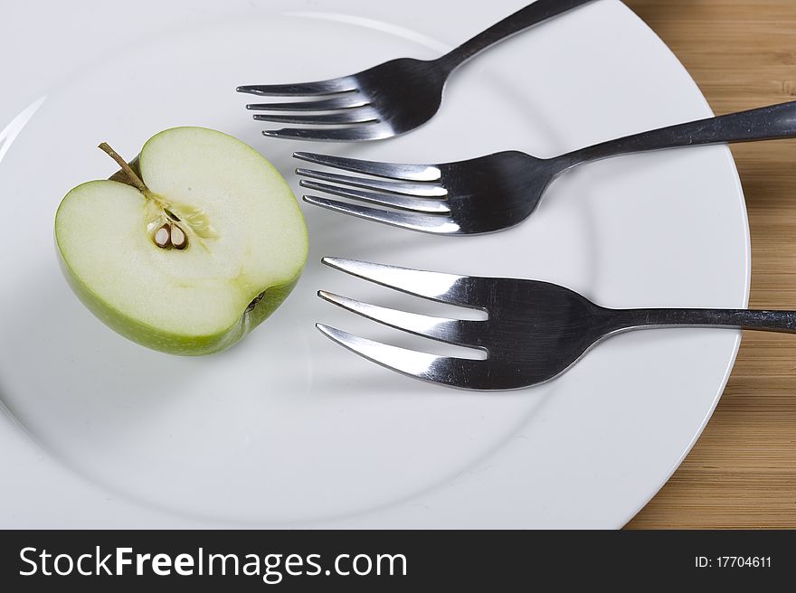 Green apple on the white plate with fork