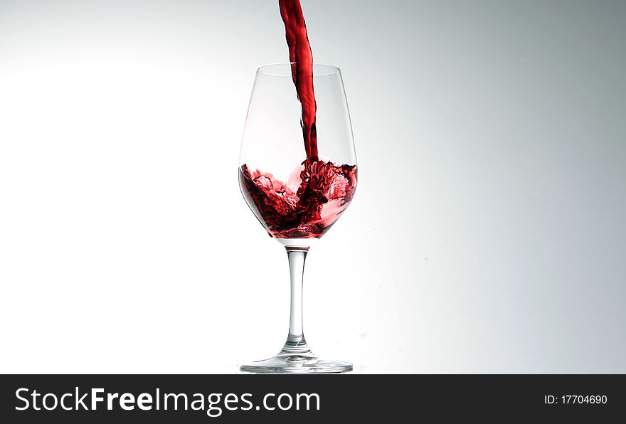 Red wine being poured in to a glass, isolated on white. Red wine being poured in to a glass, isolated on white.