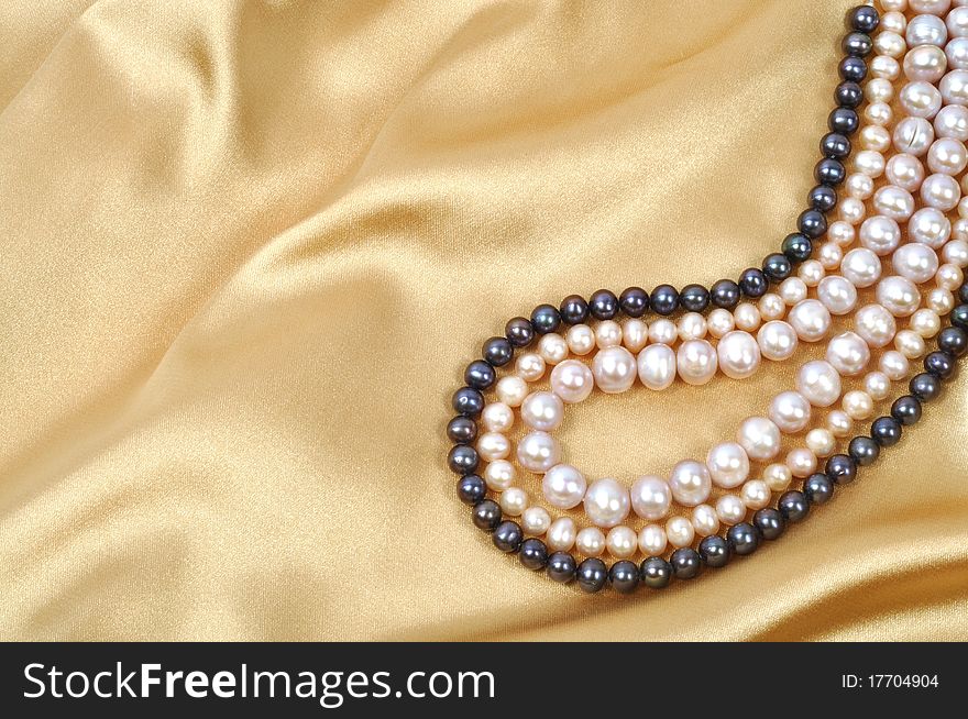 Gold silk background with pearl necklace on it. Gold silk background with pearl necklace on it