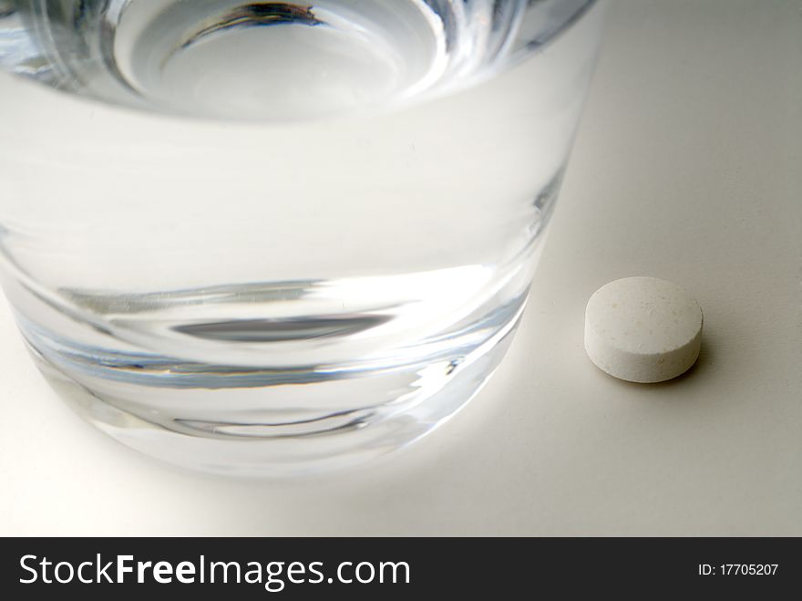 Pill next to a glass of water