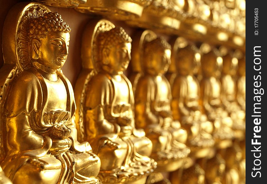 Row of small golden buddha statue in Temple of Thailand