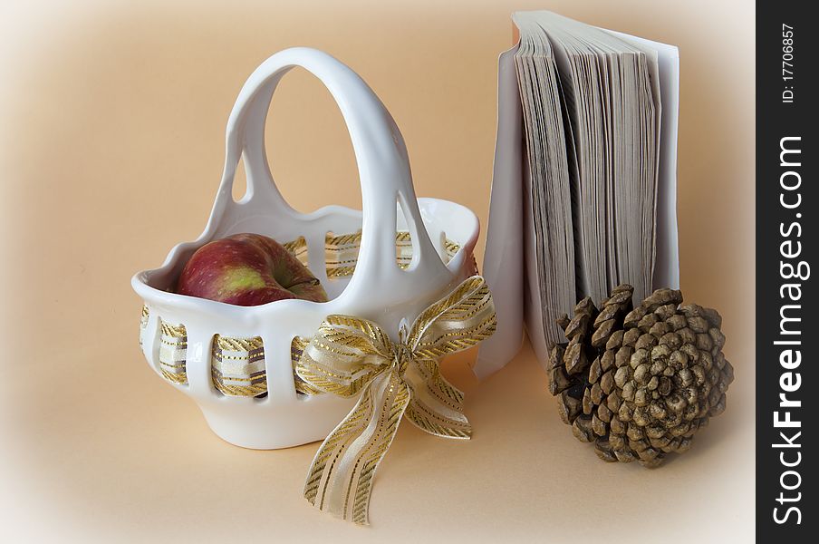 Vase with an apple and the pine cone on a beige background