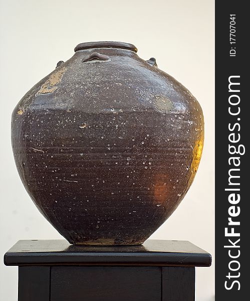 Earthen pot on a dark stand with a light background