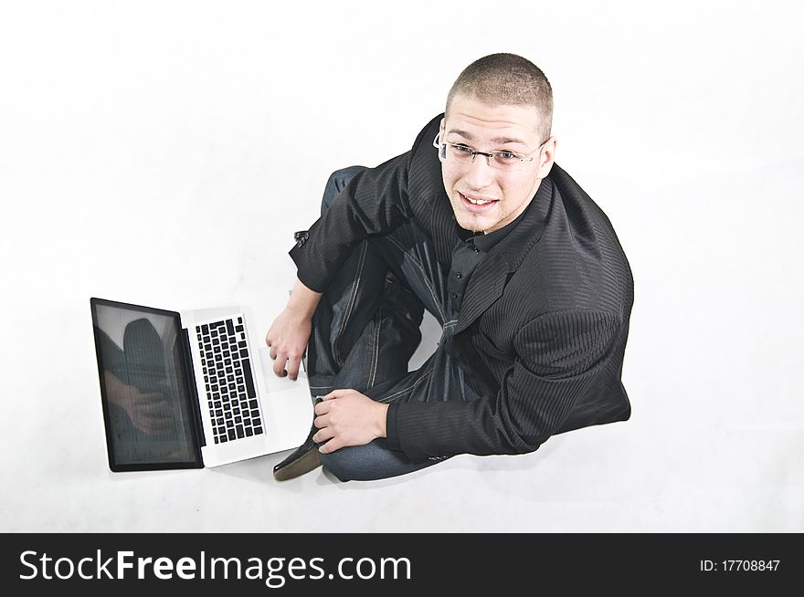 Young businessman in suit sitting on the floor with laptop