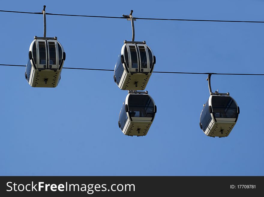 Four empty cable cars pass each other against a blue sky