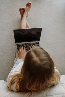 White Girl With Computer On Carpet In Bedroom Royalty Free Stock Photos