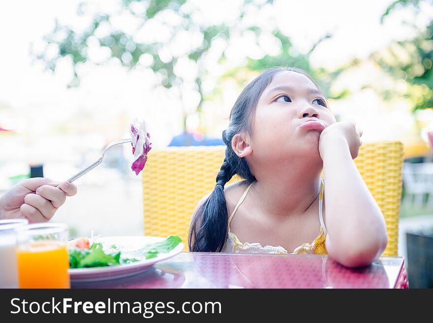 Asian child girl with expression of disgust against vegetables in salad, Refusing food concept