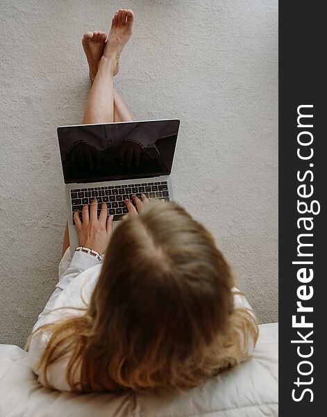 White caucasian girl with a grey computer sitting on a white and soft carpet of her bedroom. White caucasian girl with a grey computer sitting on a white and soft carpet of her bedroom