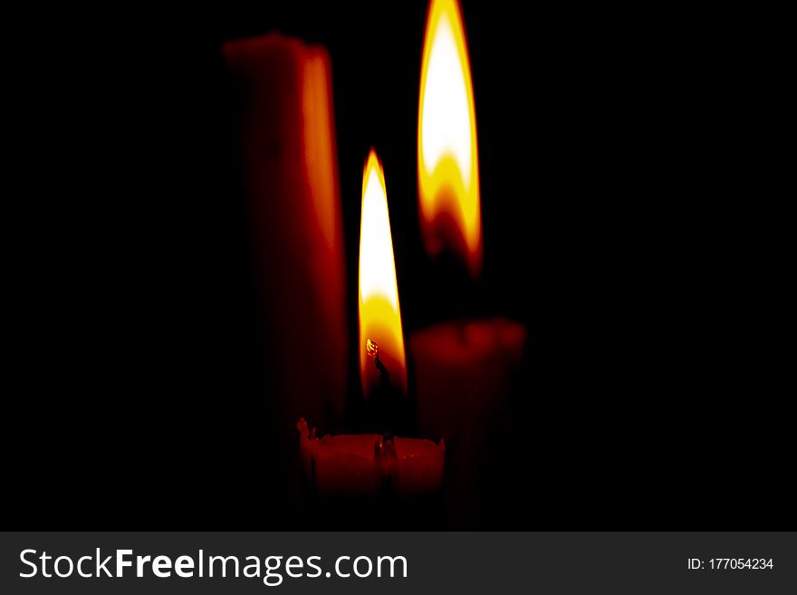 Lighted candle stands in a dark room close-up