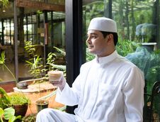 Asian Mid Aged Muslim Business Man Sit In Coffee Shop Drink Coffee With Smart Mobile Phone On Table Royalty Free Stock Photo