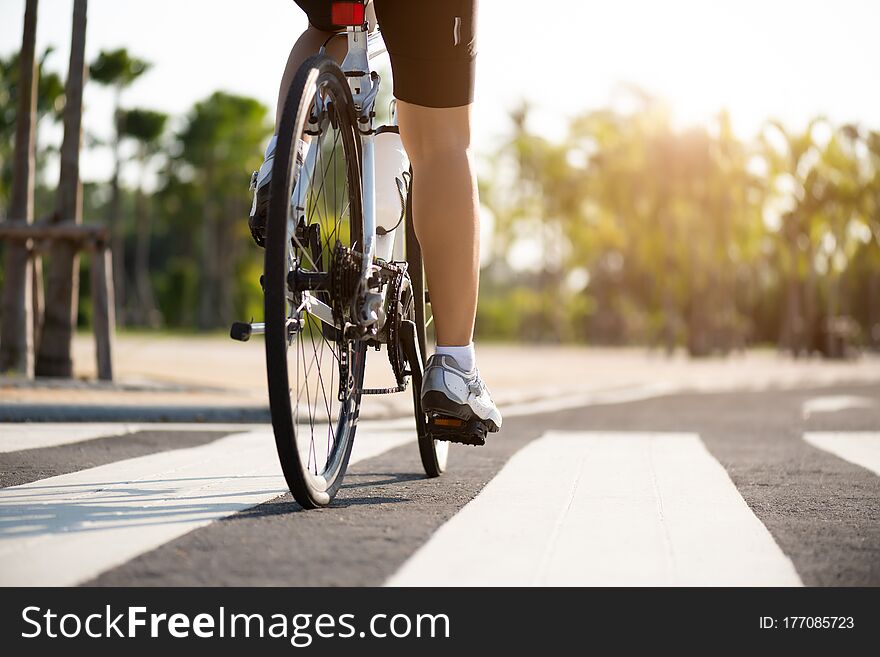 Athlete woman cyclist legs riding Mountain Bike on the road in the morning.
