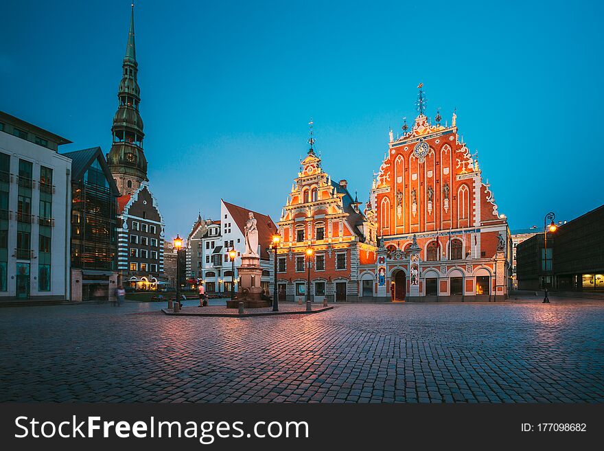 Riga, Latvia. Scenic Town Hall Square With St. Peter`s Church, Schwabe House, House Of Blackheads. Popular Showplace With Famous Landmarks On It In Bright Evening Illumination In Summer Twilight Under Blue Sky.
