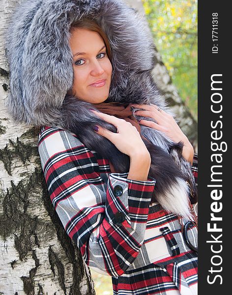 Portrait of a girl with a fur hood in the birch forest