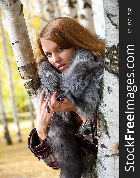 Portrait of a girl with a fur collar in the birch forest