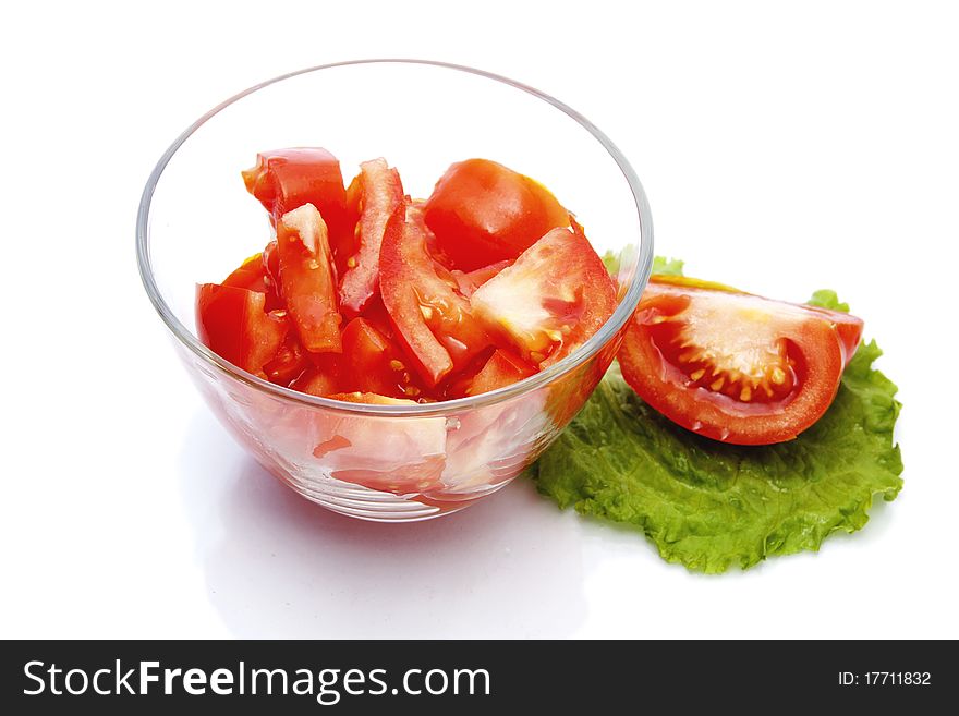 Red tomato, sliced into pieces, in a glass bowl on white background. Red tomato, sliced into pieces, in a glass bowl on white background