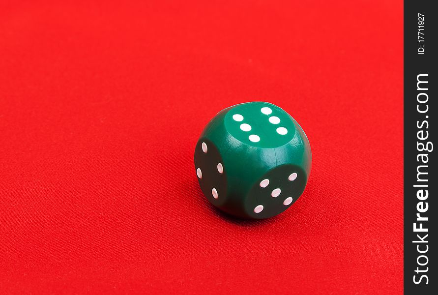 Green plastic dice on a red fabric background