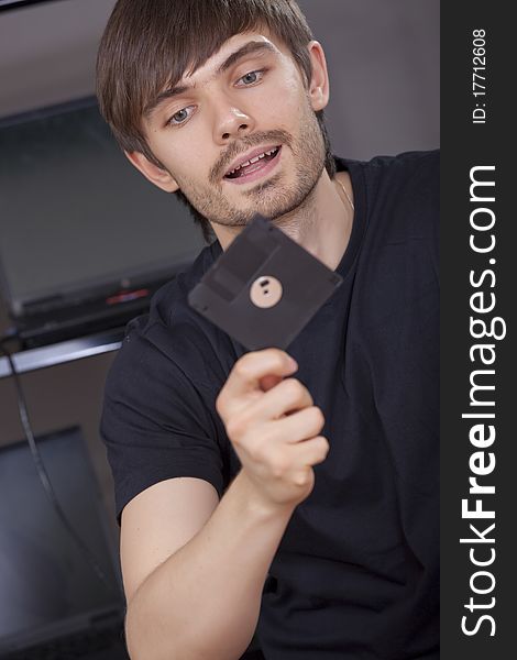 Computer hacker holding floppy disk in his hand