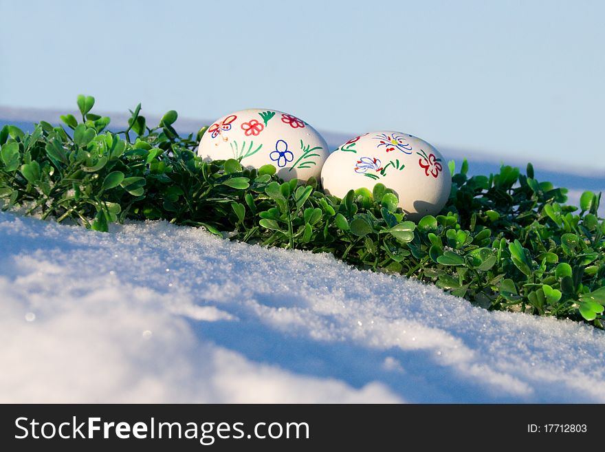 Easter eggs on a snowy hill on the skyline and the green