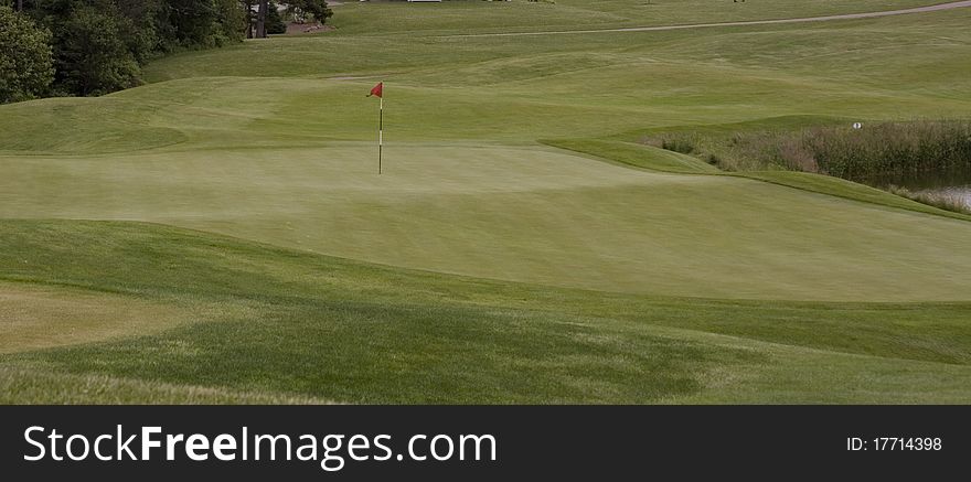 Red golf flag and pin on a green. Red golf flag and pin on a green