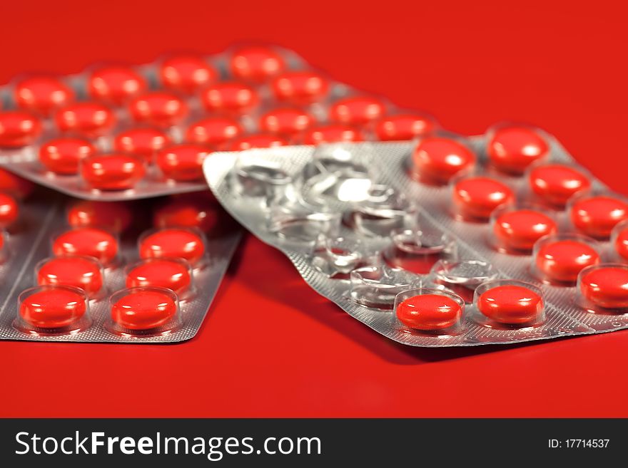 Pills in blister pack in red background, macro